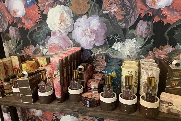 perfume bottles on a shelf in front of a floral wallpaper
