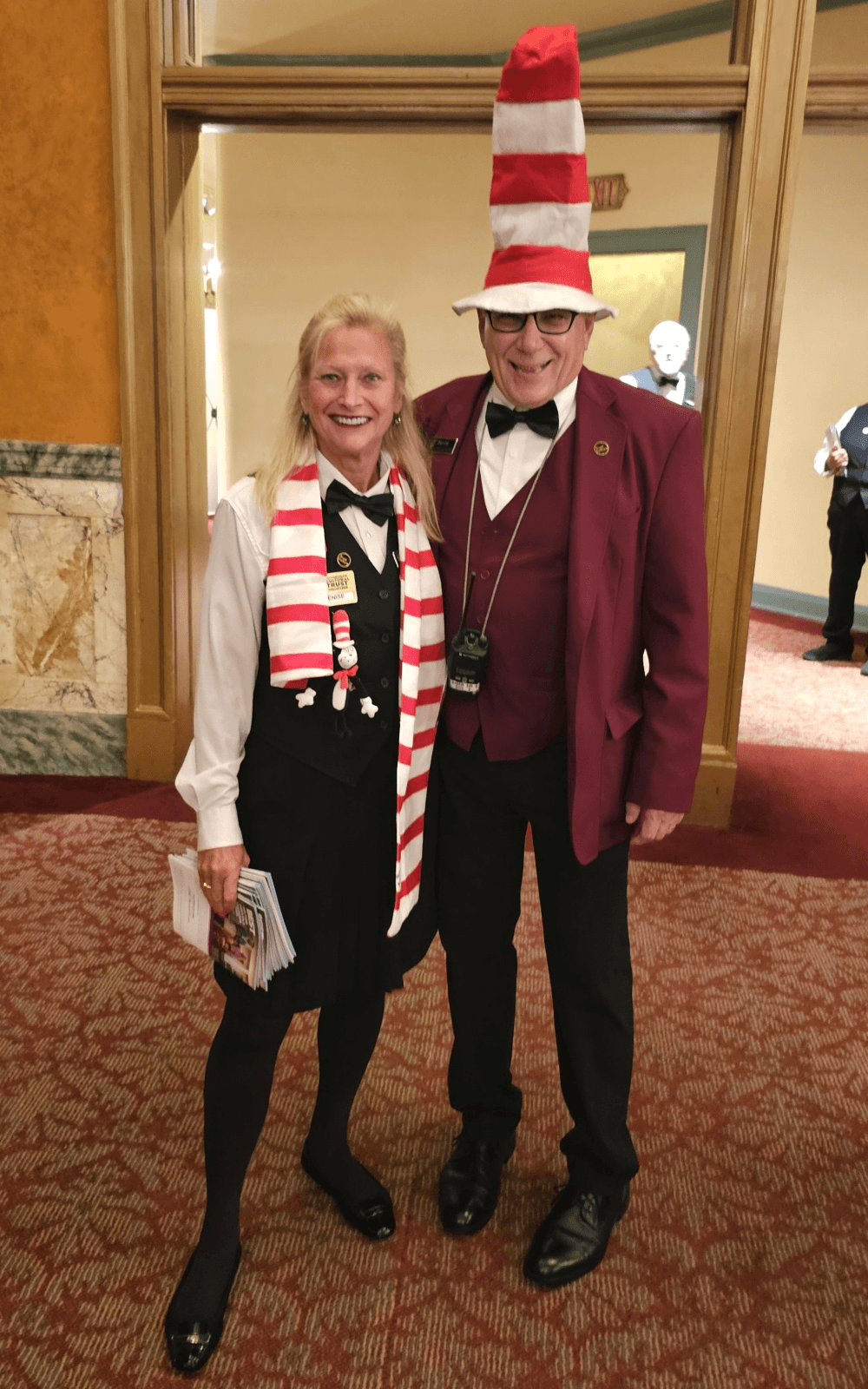 two volunteers wearing a red and white striped scarf and a tall hat.