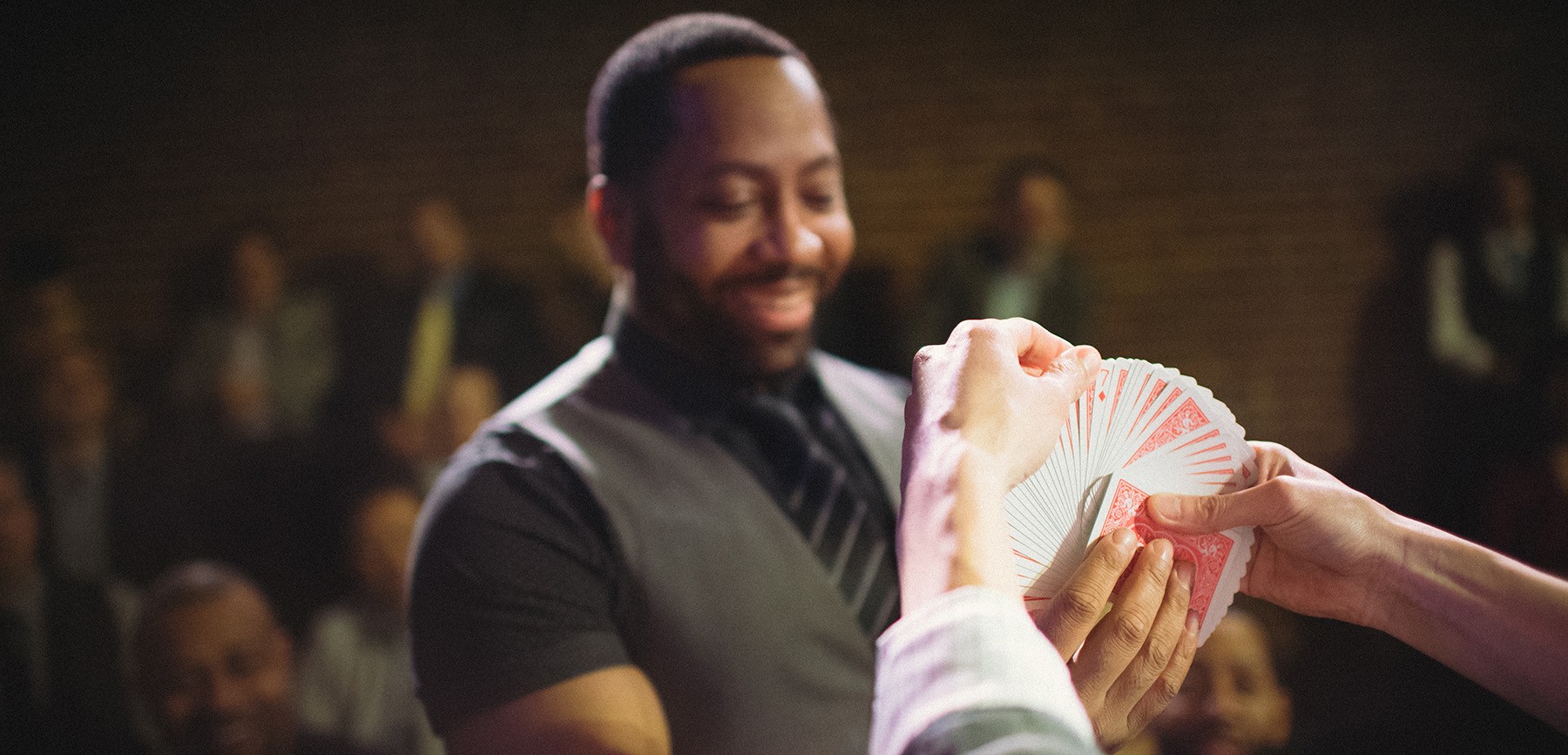 an audience member chooses a card out of a deck being held by a magician