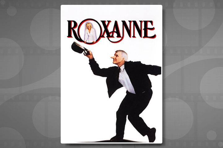 Movie poster with the title Roxanne. A man in a white shirt and black suit with an unnaturally long nose holds up black hat in one hand.