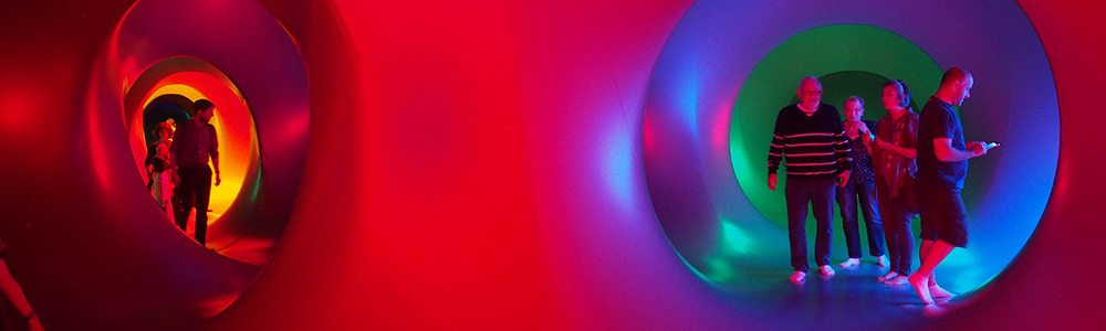 a group of people walk through a red and pink inflatable structure