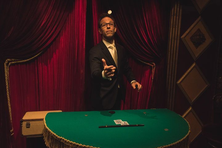 A man at green casino card table throws a coin up into the air.