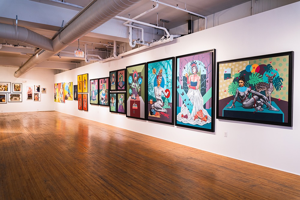a gallery space with many paintings hung on the walls