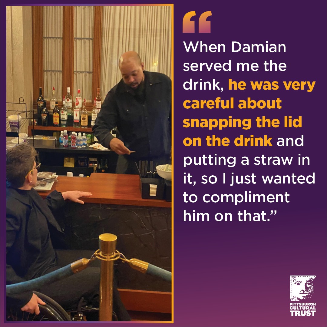 Tess orders at the accessible bar counter in the Benedum lobby while a bar tender makes her a drink.