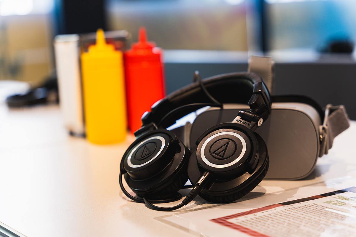 a VR headset and headphones sit on a diner table. condiment bottles and napkins are in the background