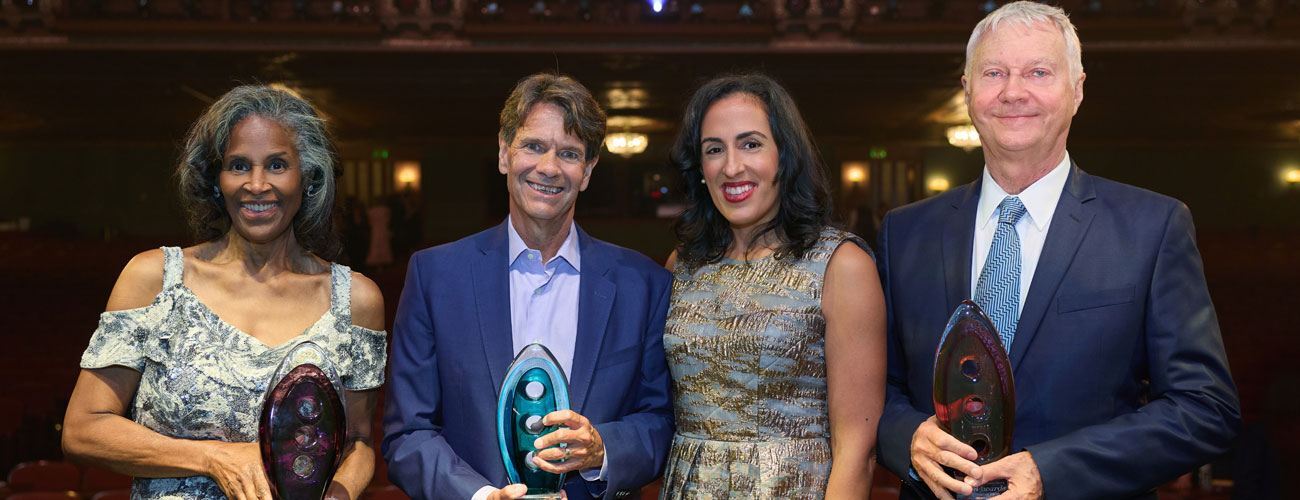 The three Icon Awardees hold up their trophies with Kendra Whitlock Ingram beside them. Behind the group, you can see the Benedum Center auditorium.