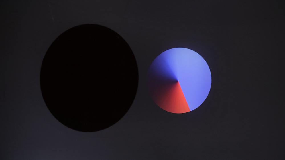 two circles on a grey background. one is black and the other is a circular gradient of red and blue