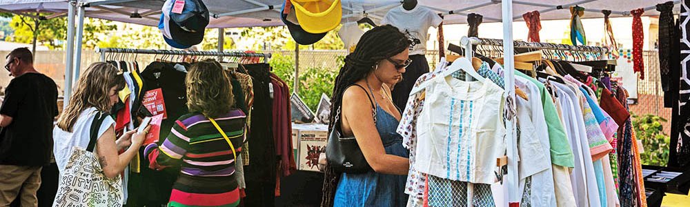 People looking through clothing at an outdoor pop-up shop.