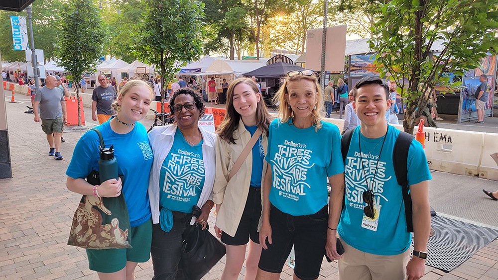 five people wearing blue t-shirts stand together and smile