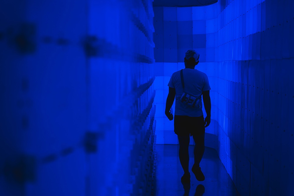 a person walks down a corridor made of blue light up blocks