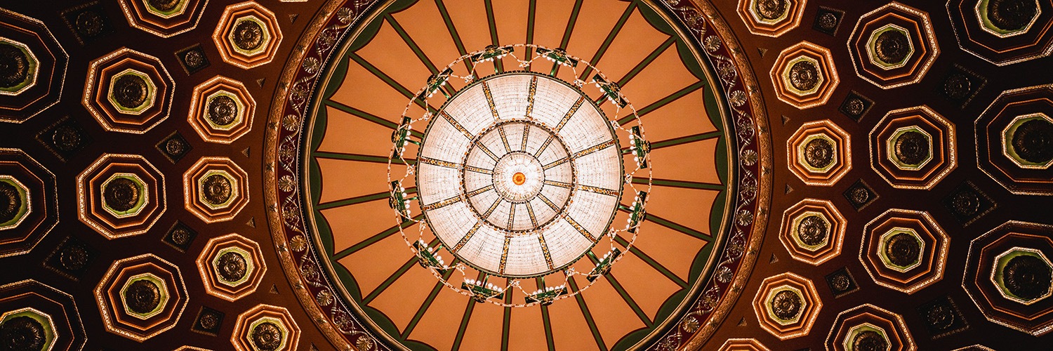 the intricate gold and green ceiling and chandelier of the benedum center.