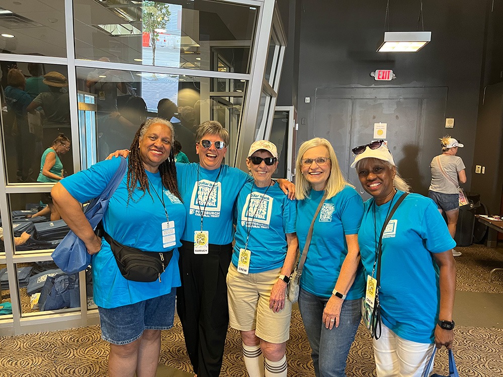 five people wearing blue t-shirts stand together and smile