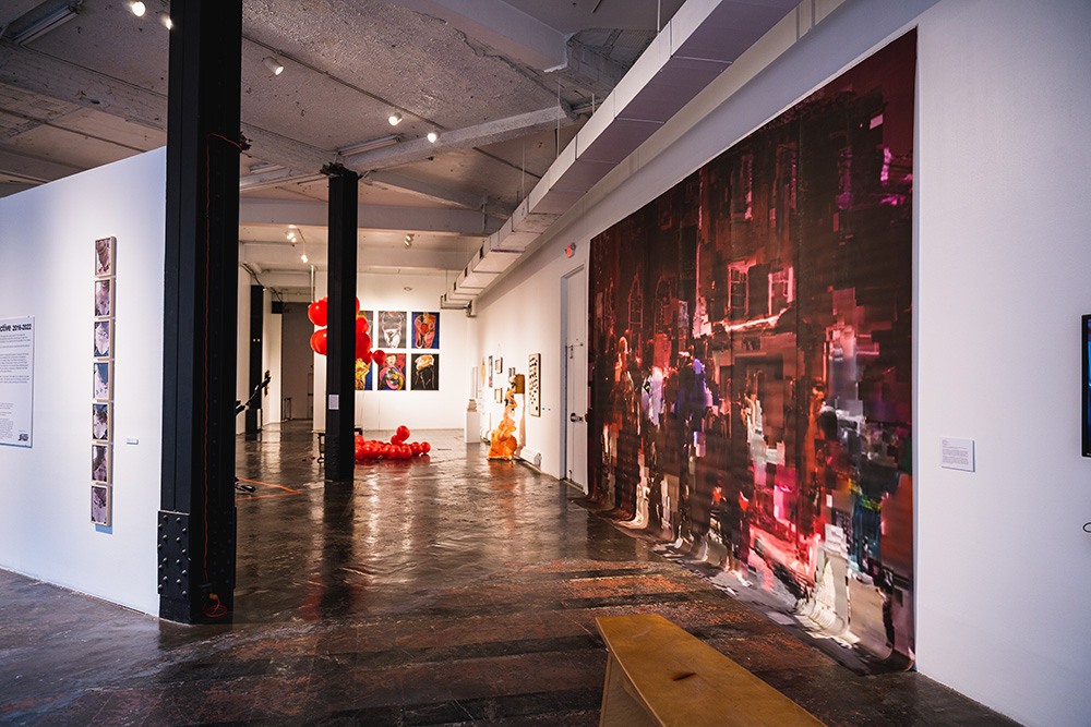 a large red and maroon mural hangs in a gallery space.