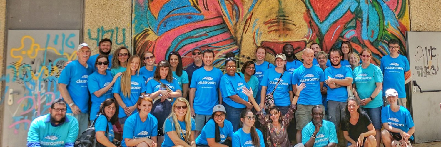 Group of visual arts teachers, visual artists,and arts administrators stand in front of colorful mural during Visual Arts & Culture Study Seminar in Israel