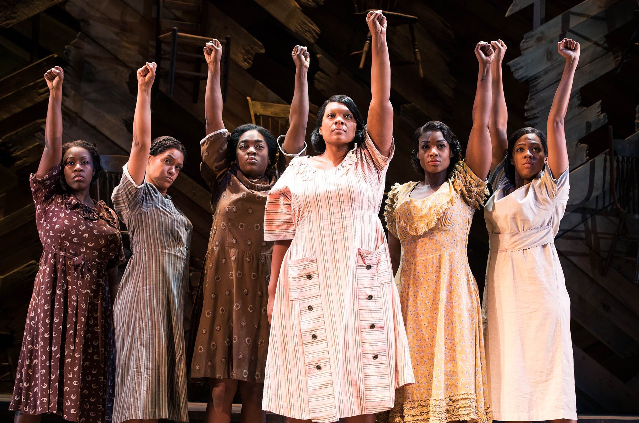 Five women raising a fist in the air