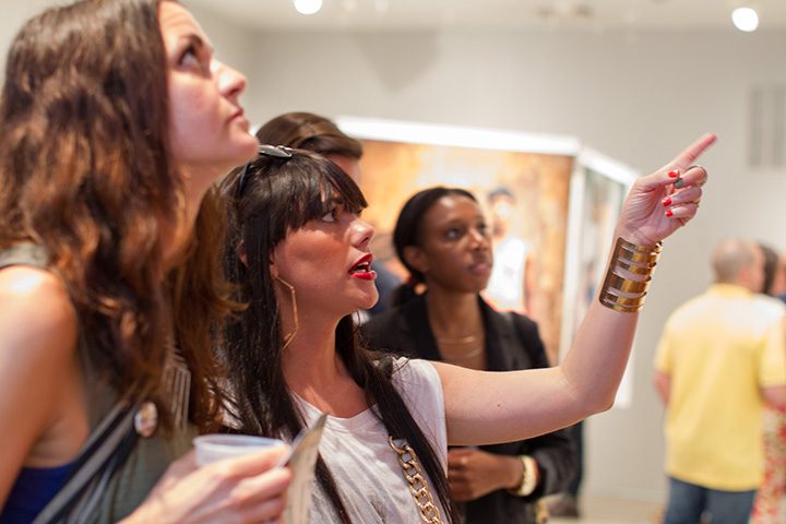 a patron points out elements of an art exhibit to a friend