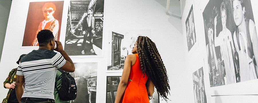 two people look up at printed photos hung on the walls of the gallery