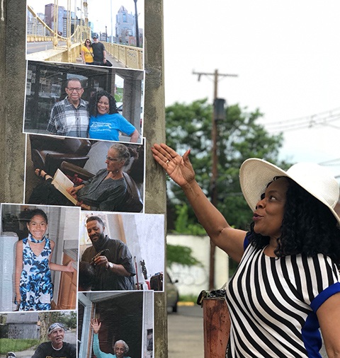 woman proudly points to her own portrait at the Afro American Music Institute