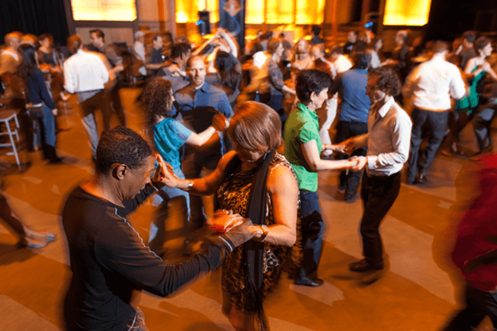 dozens of salsa dancers enjoy taking the floor with their partners