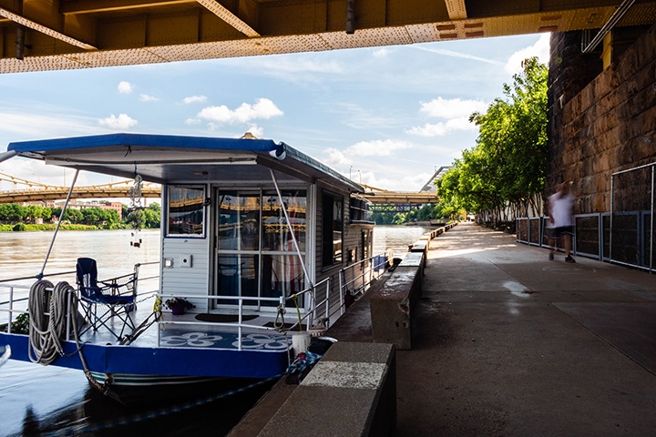 A house boat moored on the side of the riverfront path