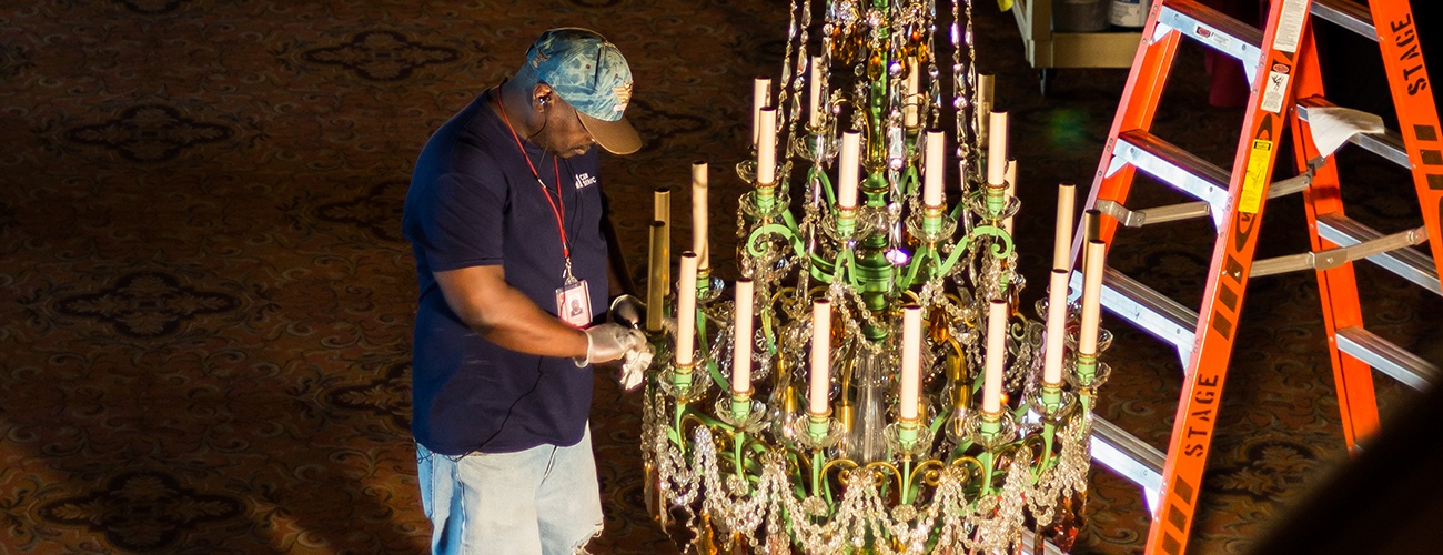 A worker cleans and polishes a chandelier in the Benedum Center