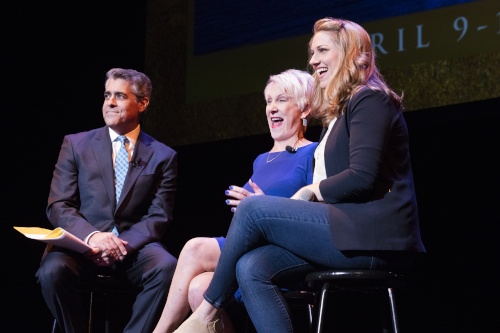 one man and two women sitting together on a stage, smiling and looking out