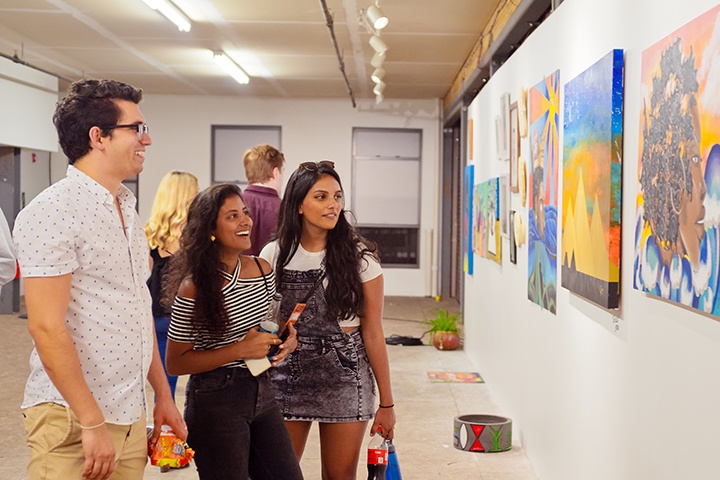 three college students looking at a painting at a gallery crawl