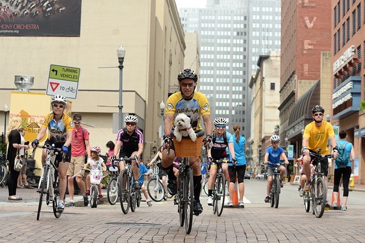 a group of bikers ride downtown during an open streets pittsburgh event