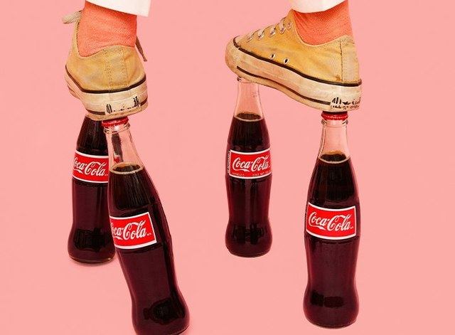 a photo from the locher + locher exhibition showing two feet balancing on four glass coke bottles