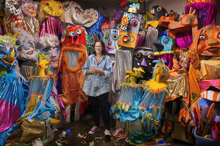 a photo of a person standing in front of a large collection of colorful puppets