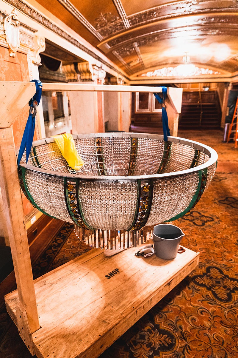 Chandelier's base removed for cleaning, pictured with household items rag and bucket