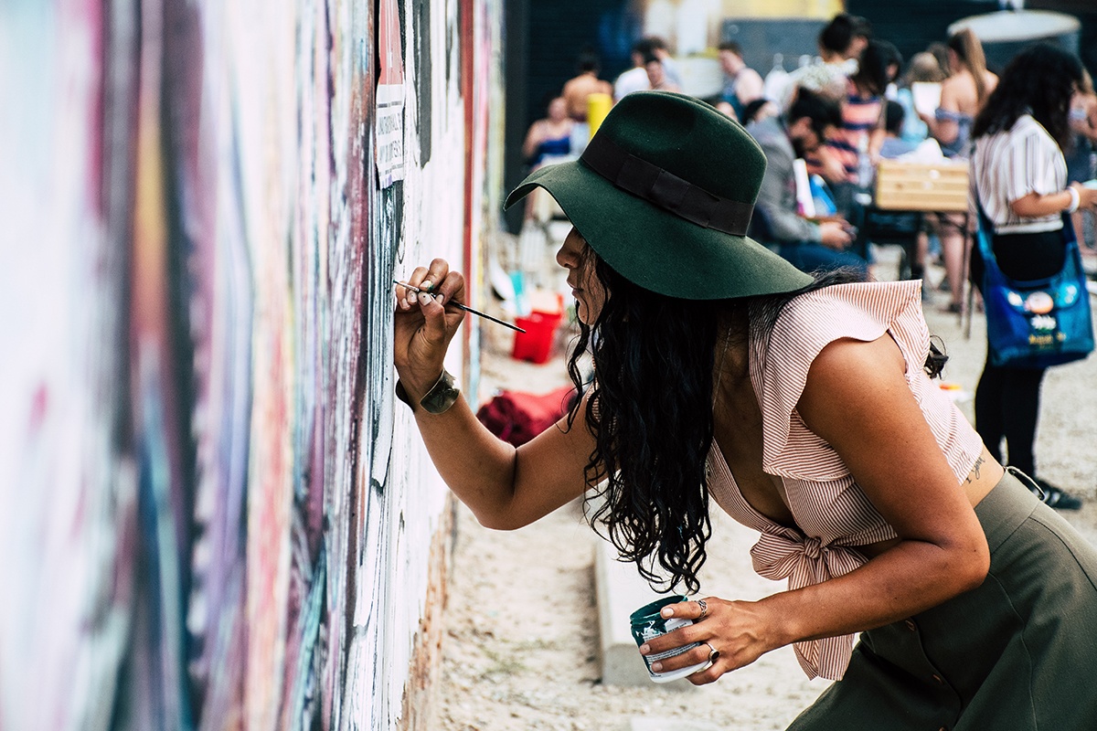 a woman paints on a large canvas hanging on a wall