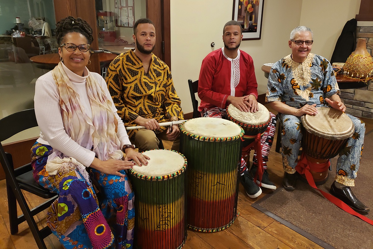 members of the ibeji drum circle sit with their drums