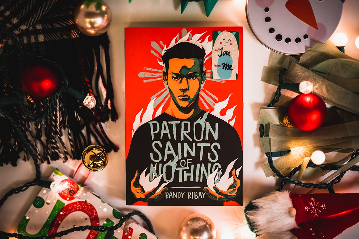 a photo of randy ribay's book 'patron saints of nothing' surrounded by holiday decorations