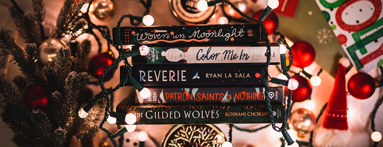 the spines of five books lined up next to each other, surrounded by holiday decorations