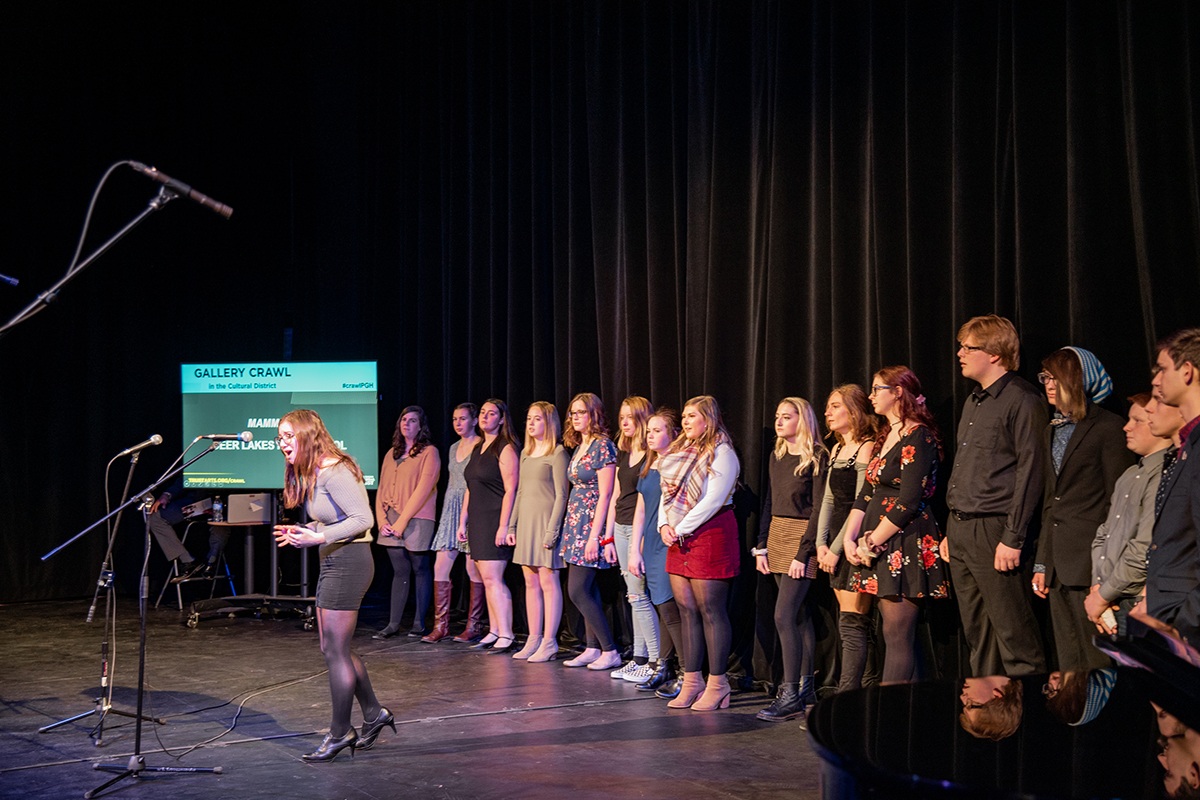 a group of high school students performing a song in a theater