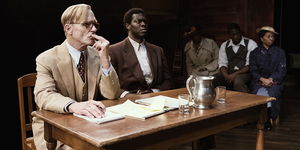 Ed Harris, left, sits at a courtroom table with another actor.