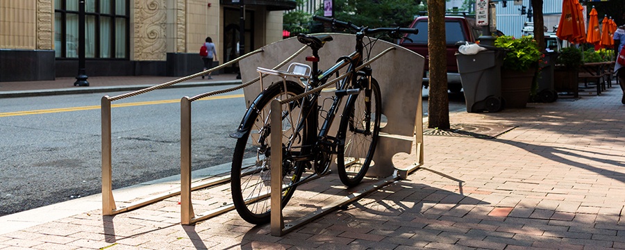 a bike locked to a metal pittsburgh public art bike rack that looks like the bridge and strings of a violin