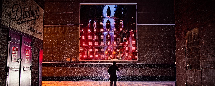 man standing in front of cell phone disco on a snowy evening