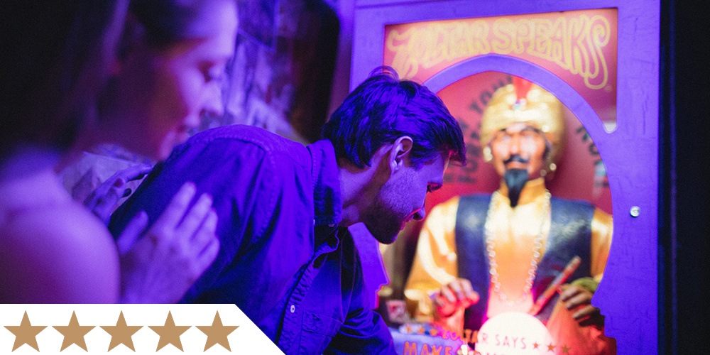 two visitors interact with liberty magic's fortune-telling zoltar machine