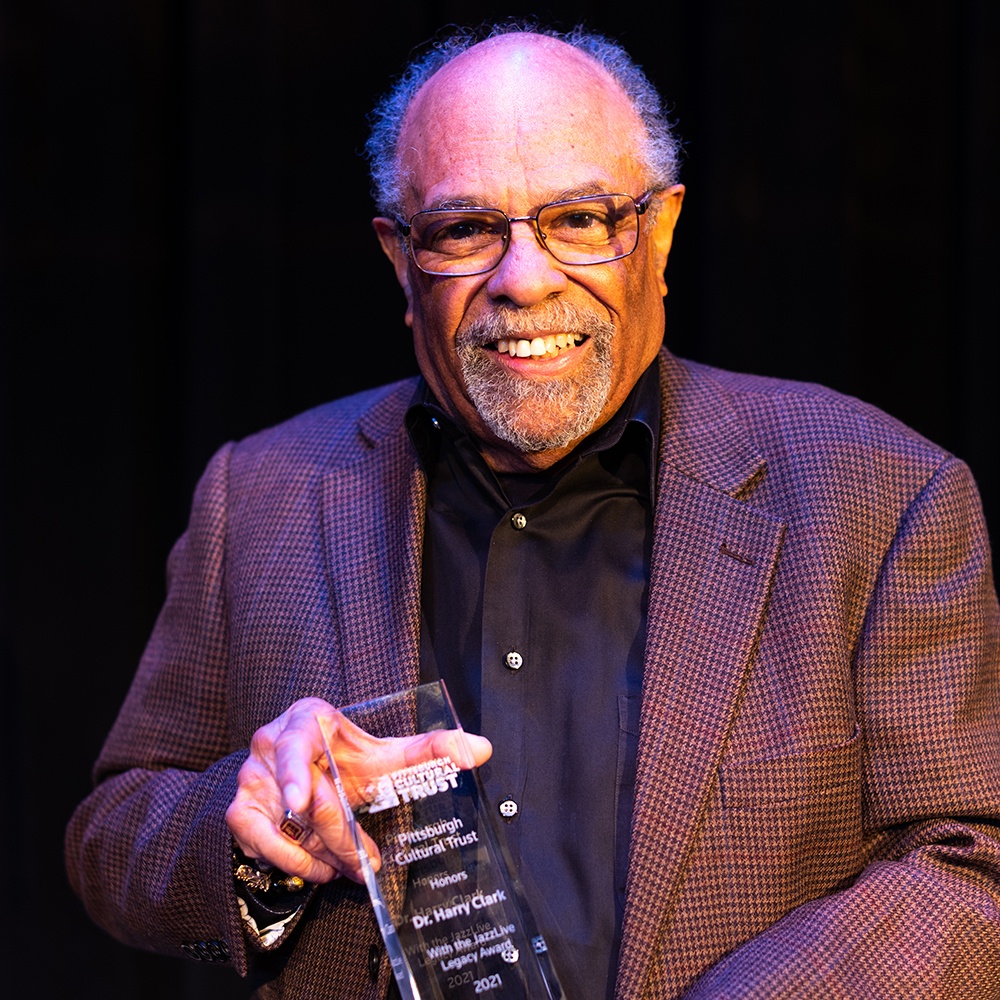 Dr. Harry Clark smiling and holding a glass award