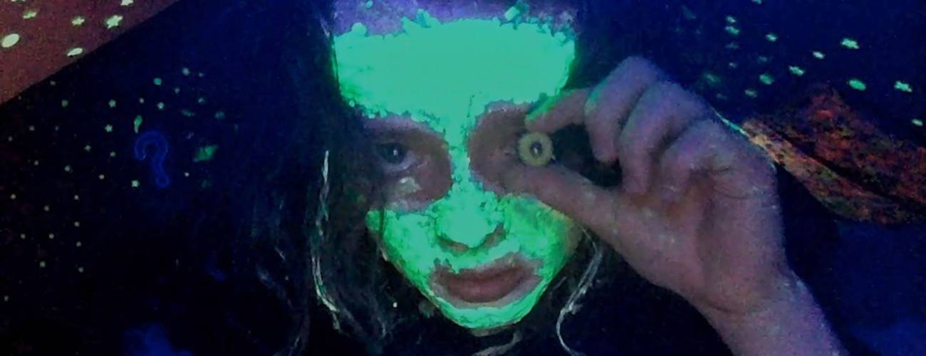 a girl covered in glow in the dark facepaint looking at the camera