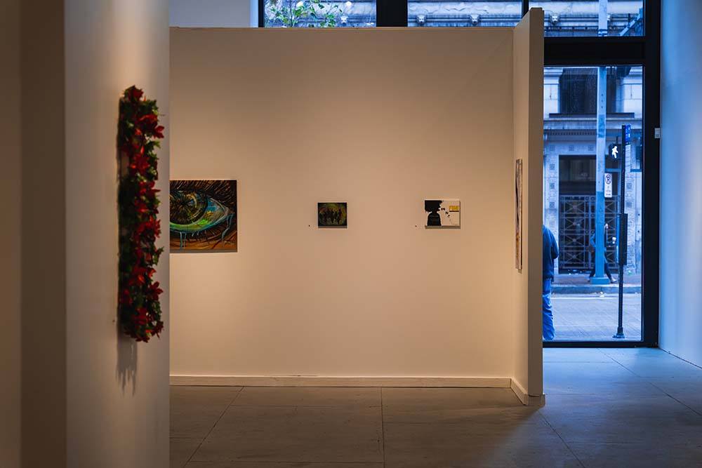 A gallery wall with three abstract paintings hung on it