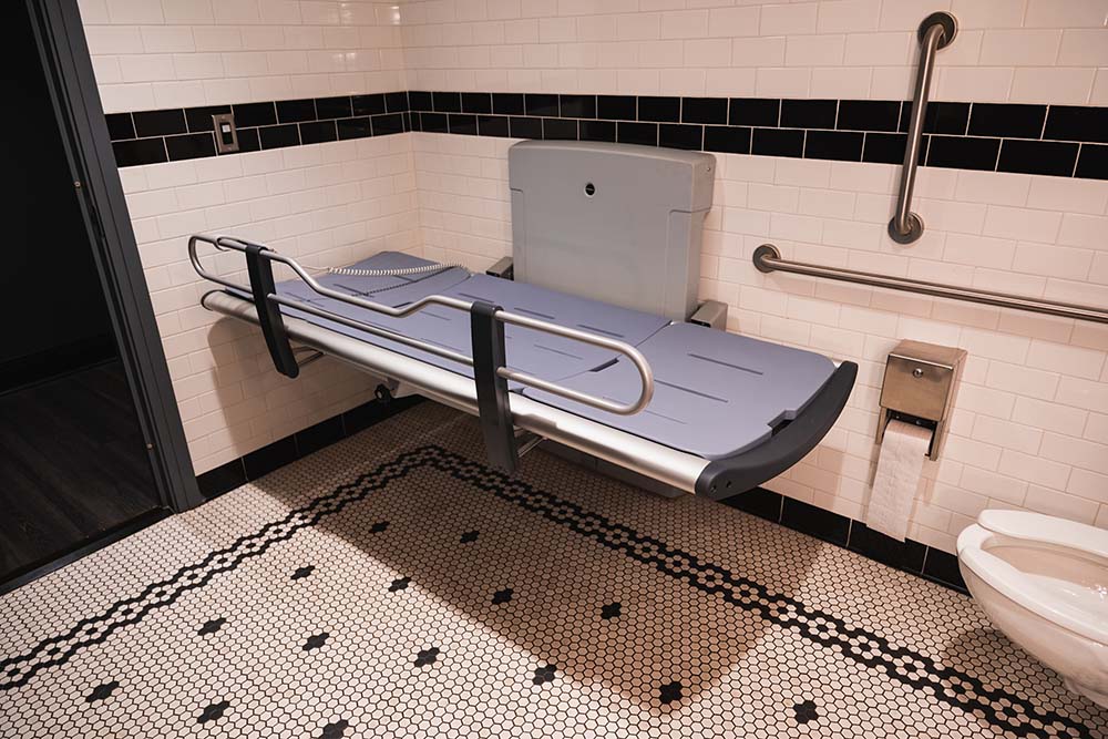 a large, fold-out adult changing table in a large accessible bathroom