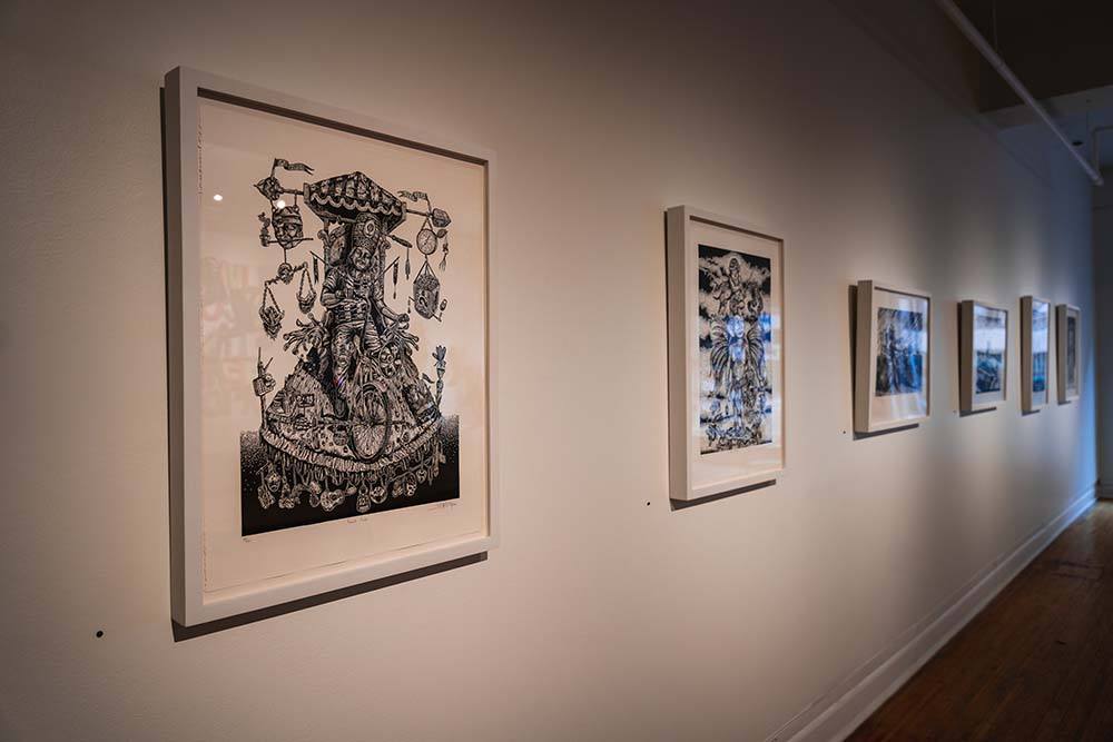 A gallery wall hung with six framed black and white drawings