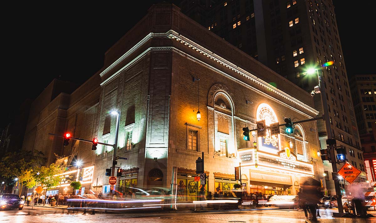 The Benedum Center exterior at night, with trails of light and shadow from passing cars and pedestrians