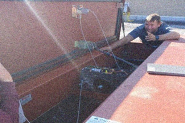 A man kneels against an open smoke hatch.