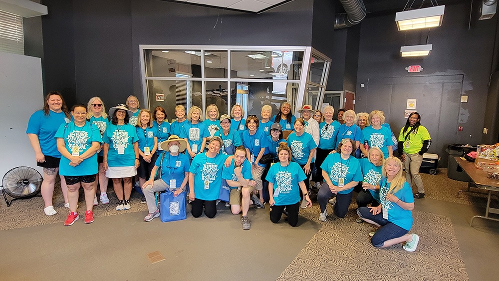 a large group of people all wearing blue t-shirts stand in a line a smile