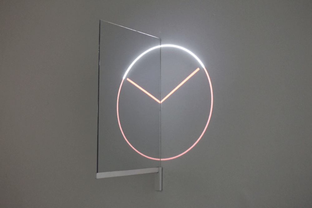 a piece of glass sticking out perpendicular from a white wall. a projection of simple analog clock hands is centered on the wall, with the piece of glass sitting down the center.