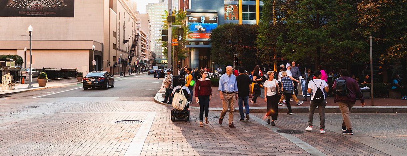 a group of people crossing an urban street at sunset